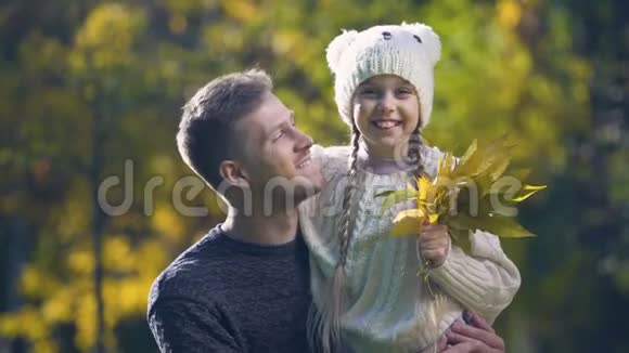 父亲抱着女儿戴着滑稽的帽子一起度过空闲时间秋天散步视频的预览图
