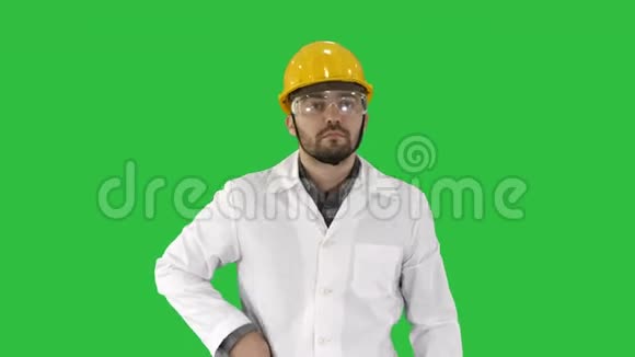 工程师戴着防护眼镜和帽子走路在绿色屏幕上拿起电话Chroma键视频的预览图