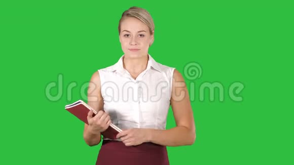 穿正装的女人打开笔记本在一个绿色屏幕上看里面彩色键视频的预览图