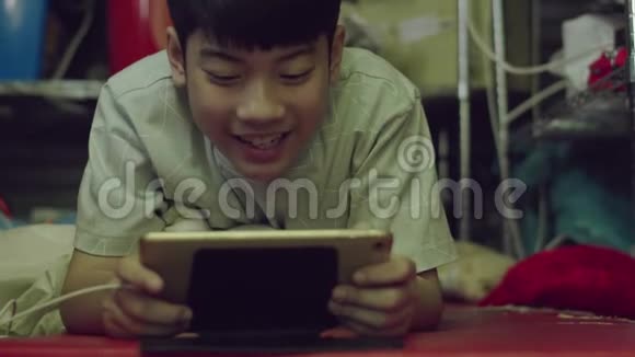 年轻的亚洲快乐男孩用笑脸在平板电脑上视频的预览图