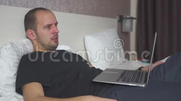 一个躺在床上用笔记本电脑工作的人真想睡觉揉揉眼睛视频的预览图