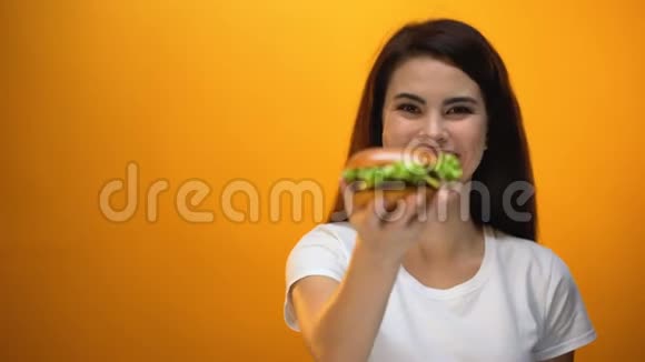 快乐女孩向镜头展示汉堡包快餐店满意顾客视频的预览图