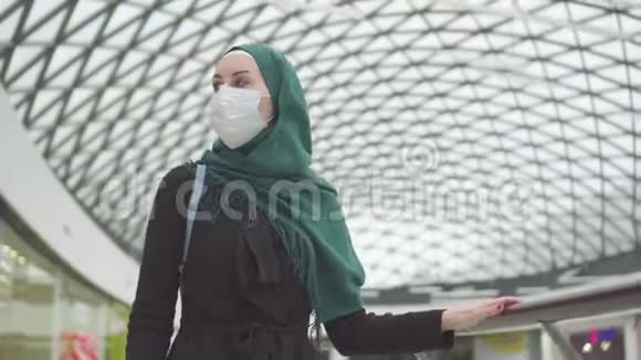 肖像漂亮的穆斯林妇女戴着头巾背着背包脸上戴着医疗面具去购物视频的预览图