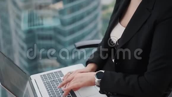 一位商务女性坐在办公室高层的窗户旁在笔记本电脑上工作的特写肖像视频的预览图