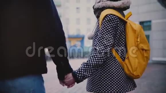 一个穿着冬装笑容满面的欧洲女孩和男友手牵手在外面约会视频的预览图