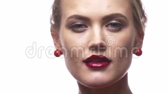 一个涂着红口红的女人正在戴上她那副白色时髦的太阳镜闭上嘴视频的预览图