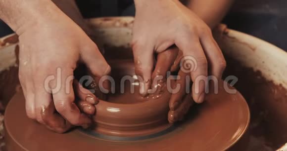 一个男人和一个女人的手在陶工的泥上车轮塑造了一个花瓶陶工在一个陶工作坊里用粘土干活视频的预览图