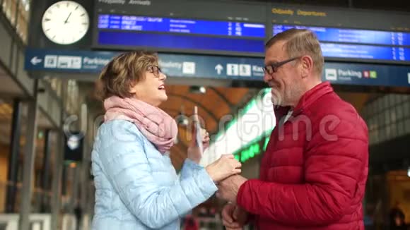 一个女人喜欢即将到来的旅行拥抱和感谢男人在火车站快乐的老年夫妇家庭旅行视频的预览图