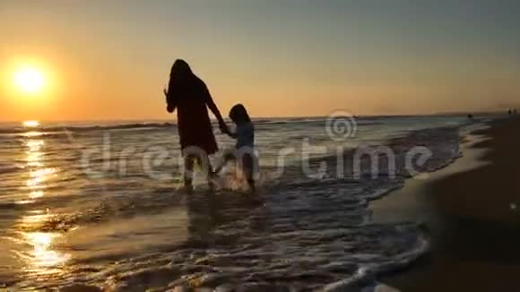 在海边散步的母亲和孩子的剪影视频的预览图