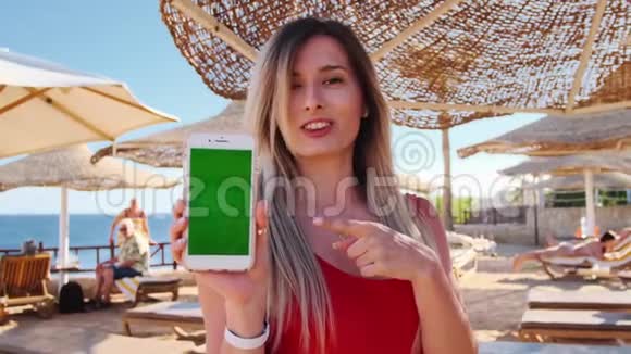 度假的女孩在户外展示绿色屏幕智能手机将女性手握住并使用手机智能手机视频的预览图