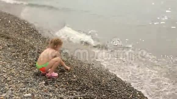 一个小女孩把石头扔进海里暑假在水边视频的预览图