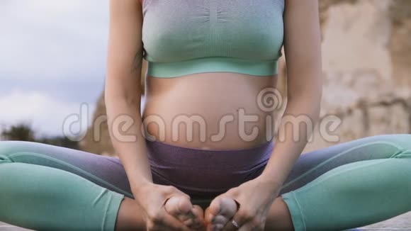 孕妇坐在莲花户外做瑜伽呼吸练习视频的预览图