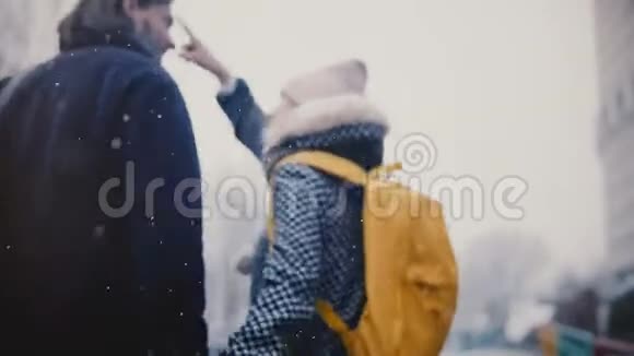 后景快乐轻松的年轻男女带着鲜艳的黄色背包一起散步在寒冷的雪天牵着手视频的预览图