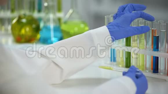 实验室助理用蓝色化学物质将黄色液体滴入试管中视频的预览图