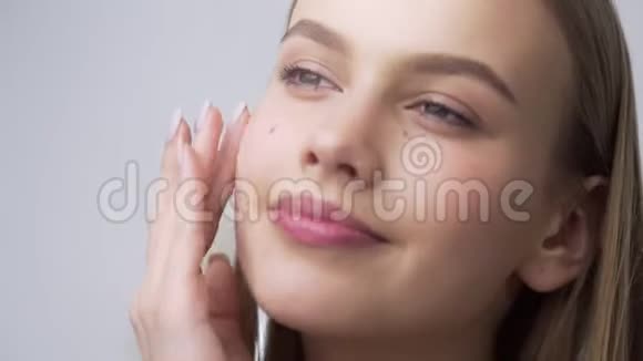 年轻漂亮的女人把面霜涂在颧骨上把面霜涂成圆形皮肤护理天然的视频的预览图