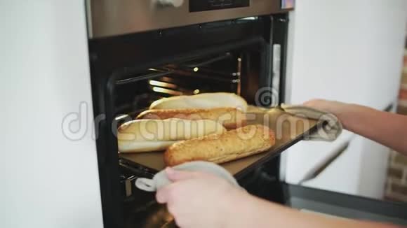 一只雌性把面包放进烤箱视频的预览图