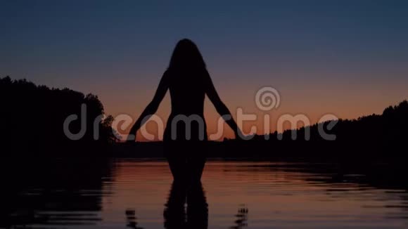 夕阳西下的湖水中女人的双膝伸展着手臂视频的预览图