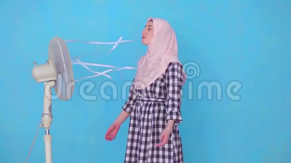 在炎热的天气里年轻的穆斯林妇女被风扇冷却视频的预览图