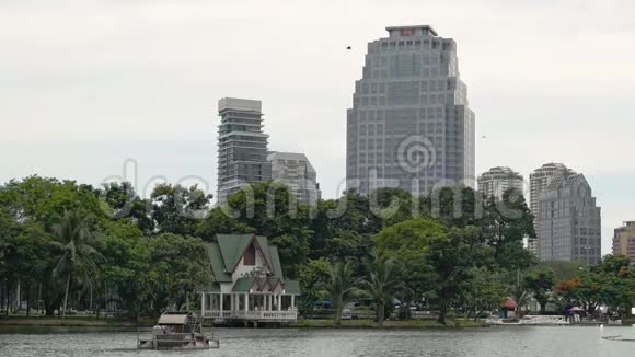 曼谷的兰皮尼公园摩天大楼旁边的绿色公园里美丽的湖宁静的城市景观视频的预览图