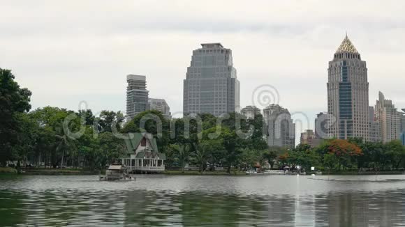 高大的建筑物和树木反映在湖面上白天在绿色城市公园的一个大湖视频的预览图