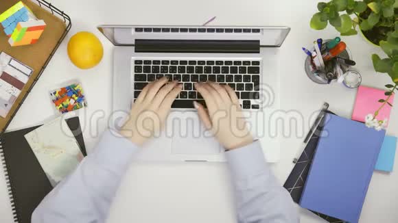 使用触摸板和键盘笔记本电脑打字的蓝衬衫女性手的俯视图视频的预览图