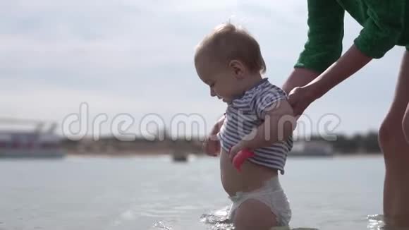 快乐的孩子和母亲一起在水中行走母亲会缓慢地保护他视频的预览图