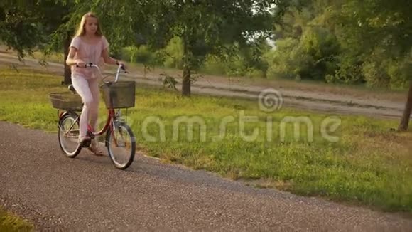 女孩骑自行车在公园小巷慢动作视频的预览图