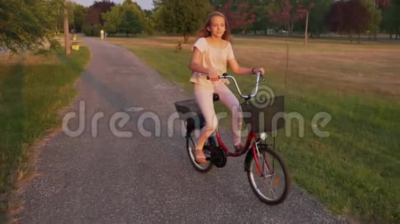 女孩骑自行车在公园小巷慢动作视频的预览图