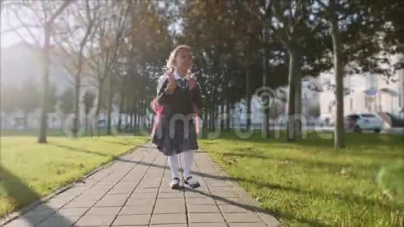 穿着校服的小女孩在阳光明媚的天气里在公园里散步视频的预览图