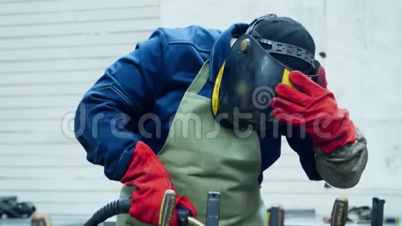 人穿着防护服和面罩焊接金属毛坯安全帽焊工视频的预览图
