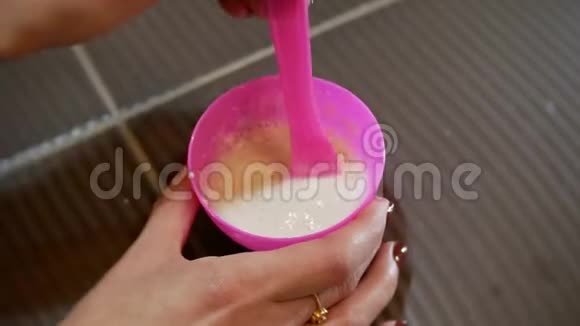 4Kcosmetology概念女人手在粉红色的杯子里搅拌海藻酸钠面膜视频的预览图