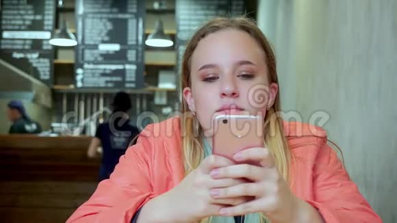 年轻迷人的女孩在咖啡馆里看智能手机她难过视频的预览图