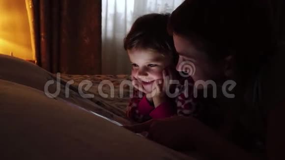 妈妈和她的小女儿在家看平板电脑视频的预览图