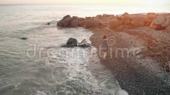 日落时漫步海滩的女人视频的预览图