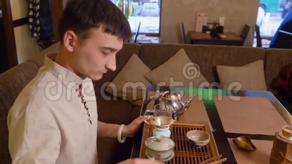 茶师在仪式上用热水暖茶碗和公平水壶视频的预览图