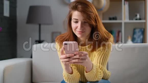 年轻快乐的女人笑着用手机应用程序与朋友在线聊天在社交媒体上写博客视频的预览图