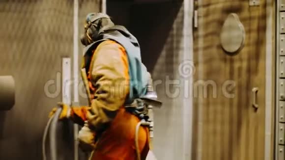 穿防化学防护服的人拿着浇水软管穿橡胶西装的工人视频的预览图