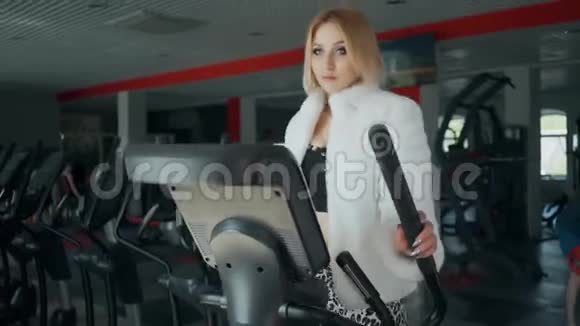 懒惰的叛逆女人穿着毛皮外套和高跟鞋在健身房锻炼有趣的动机视频的预览图