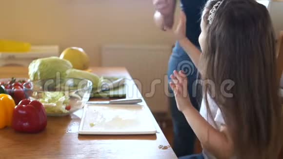 可爱的学龄前女孩在厨房里勺沙拉妈妈帮手女儿和母亲正在准备素食沙拉视频的预览图