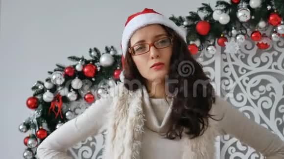 年轻的美女戴着圣诞帽戴着圣诞背景装饰脸上表情严肃视频的预览图