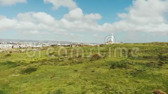 背景下白色灯塔和城市的无人机视图帕福斯塞浦路斯山城和灯塔和绿草空中射击视频的预览图