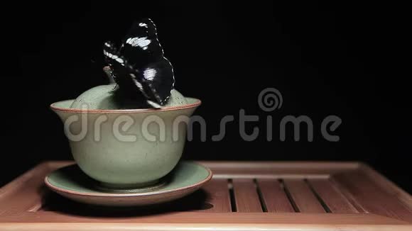 茶杯蝴蝶竹桌深色背景高清镜头视频的预览图