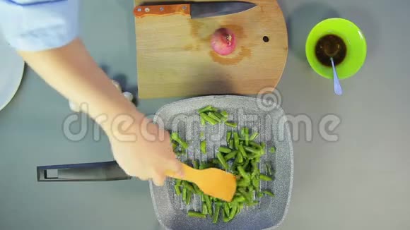 女人用木铲在平底锅里搅拌绿豆视频的预览图