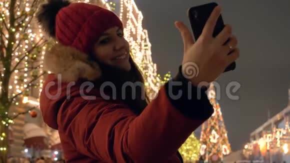 晚上在圣诞集市上站在智能手机上的女人视频的预览图
