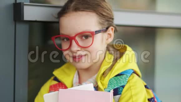 戴红眼镜的女生对着镜头微笑的照片十几岁的女孩手拿书站在靠近视频的预览图