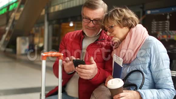 时尚的退休夫妇在火车站翻阅他们的手机照片旅途愉快视频的预览图