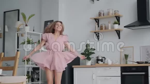 无忧无虑的女孩在厨房里跳舞很有趣3年轻女子在家穿着连衣裙视频的预览图