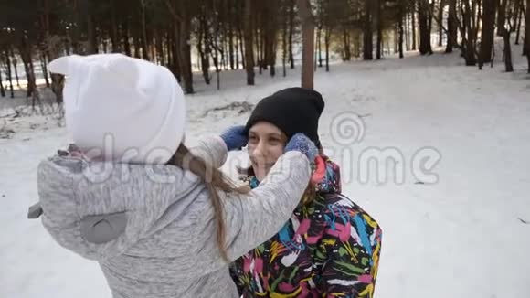妈妈把她的小女儿抱在怀里在冬天把她的帽子拉直视频的预览图