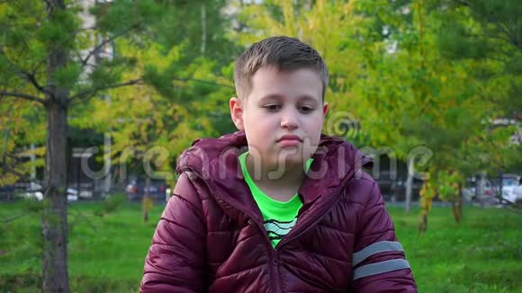 坐在公园长凳上的男孩他迷路了等着他的父母缓行视频的预览图