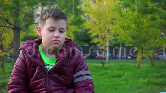 一个悲伤男孩的肖像坐在公园里他迷路了视频的预览图